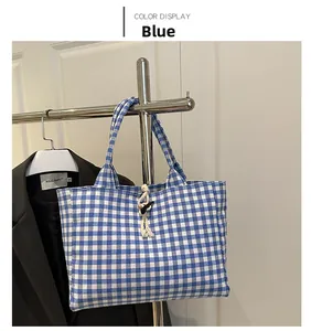 Detail of blue and white checkered canvas tote bag with woven knot and button closure