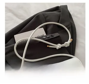 Détail de la bandoulière souple blanche sur un sac élégant avec boucle nœud dorée