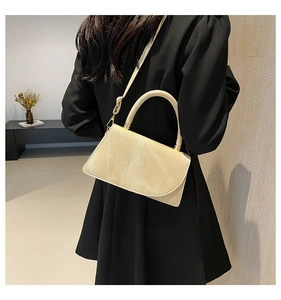 Detail showing cream-colored crossbody bag with golden metal hardware and smooth texture