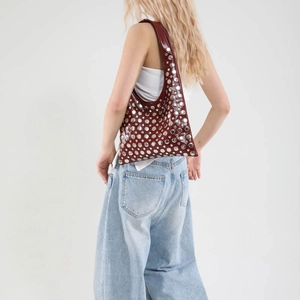 Large burgundy铆钉 hobo bucket bag with silver studs and glossy finish on a model