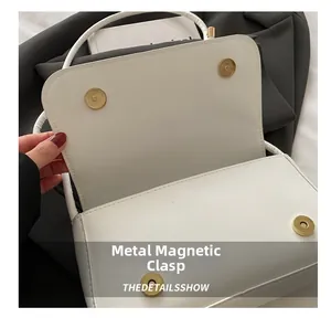 Détails d'un sac à main blanc avec deux fermoirs magnétiques dorés en métal poli
