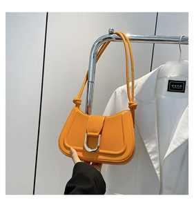 Detail of orange underarm bag featuring glossy finish and a silver U-shaped metal buckle