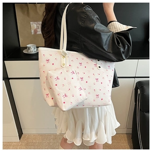 Detail of white tote bag set with pink bow and floral prints shown in a shoulder carry style