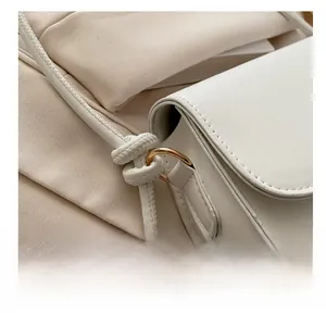 Detail of white leather handbag with golden metal ring and stylish knot shoulder strap