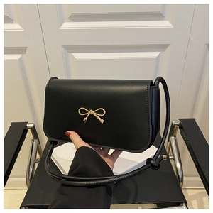 Détail du sac à bandoulière en cuir noir avec boucle de nœud doré et bandoulière