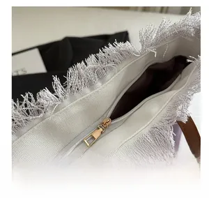 Detail of smooth metal zipper closure and white fringe trim on a purple canvas tote bag