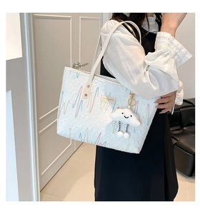 Close-up of a white canvas tote bag with colorful wave embroidery and a cute cloud charm