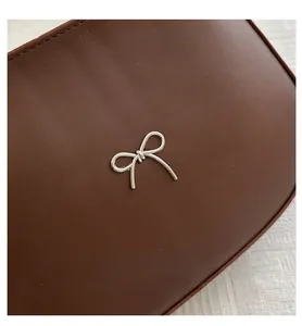 Detailed macro view of a vintage brown matte leather bag with a silver metal bow accent