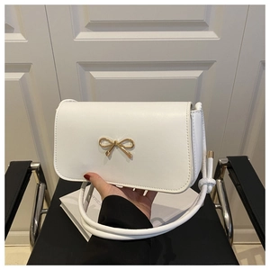 Détail d'un sac à main blanc en cuir brillant avec un fermoir doré en forme de nœud chic