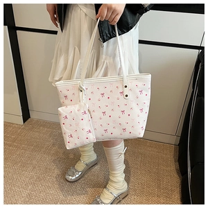 Detail of cream canvas tote bag with pink bow and floral pattern including small pouch