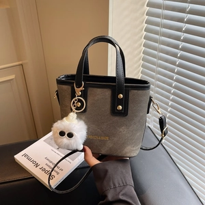 Sac seau moderne en tissu gris avec garniture en cuir noir et breloque monstre en peluche