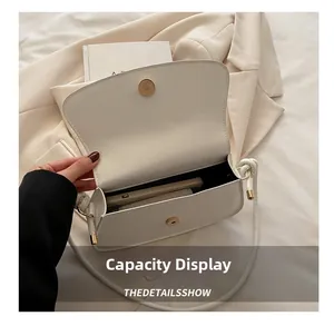 Interior view showing capacity of minimalist white shoulder bag with magnetic gold buckle