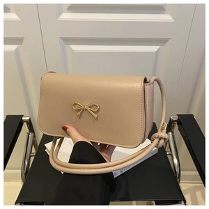 Gros plan sur le sac beige avec boucle en métal doré et bandoulière à nœud élégant