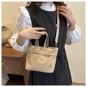 Dettaglio della borsa a tracolla in tela beige con trama stropicciata e cinturino in tessuto