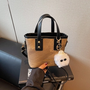 Sac seau en toile marron avec bordure en cuir noir, clous dorés et breloque peluche