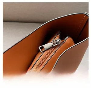 Detail of smooth metal zipper and chain strap on a caramel leather tote bag