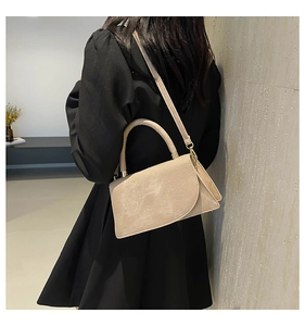 Detailed close-up of light beige suede texture and gold hardware on a crossbody bag