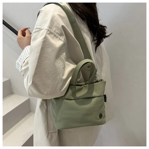 Borsa a tracolla minimalista in tela verde salvia mostrata su modella per lo stile
