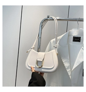 Detail of white leather half-moon shoulder bag featuring a polished gold horseshoe buckle