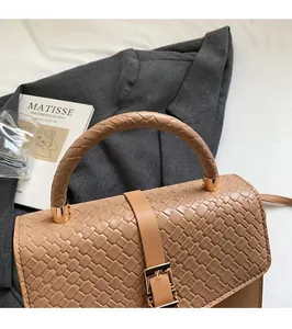 Détail du sac à main en cuir tressé marron clair avec boucle en métal et poignée