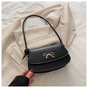 Detail of elegant black crossbody bag with golden bow hardware and knot strap design