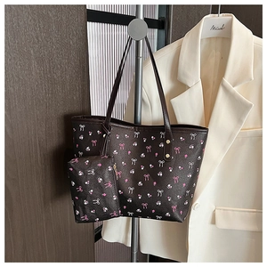 Detail of dark brown tote bag set with pink bow pattern and golden metal hardware rivets