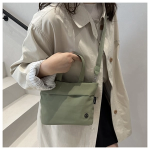 Vista dettagliata della borsa a tracolla minimalista in tela verde oliva con tracolla regolabile