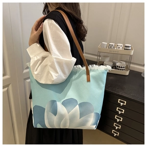 Détail du sac cabas en toile avec imprimé floral, franges blanches et bandoulière