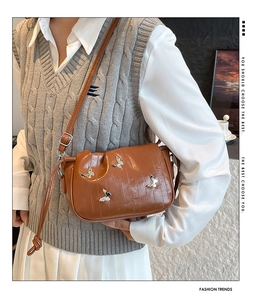 Detail of vintage brown pleated shoulder bag with four silver butterfly metal ornaments