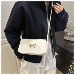 Gros plan d'un sac bandoulière blanc avec boucle nœud en métal doré et fine lanière