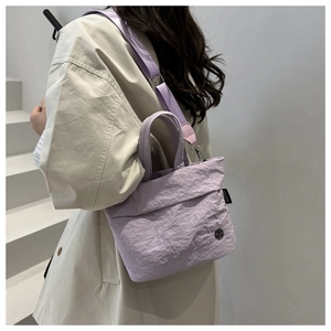 Elegante borsa a tracolla in tela lavanda indossata da una modella in un contesto minimal