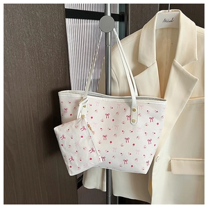 Detail of cream tote bag with pink bow pattern and matching small coin purse hanging
