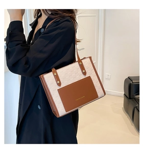 Detail of contrast stitch tote bag with cream textured body and brown leather handles