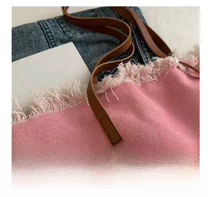 Détail du sac cabas rose avec bords à franges, bandoulière en cuir et imprimé lettres