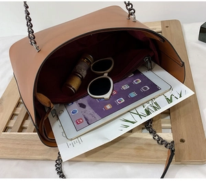 Detail view of large brown leather tote interior with chain strap and tablet capacity