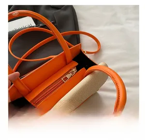 Close-up detail of smooth metal zipper closure on orange and beige woven handbag