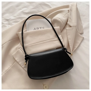 Detail of black leather half-moon bag with elegant knot strap and gold hardware accents