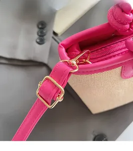 Détail de la boucle dorée et de la fermeture éclair rose sur le sac en paille