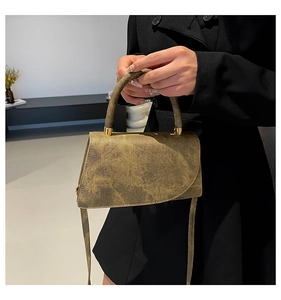 Detail of vintage green faux leather shoulder bag with gold metal hardware and top handle