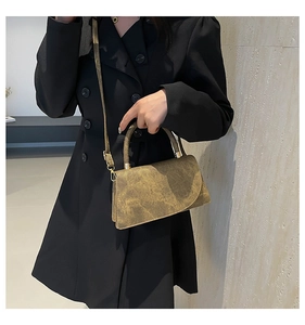 Chic retro textured crossbody bag shown on a model in a minimalist dark suit setup