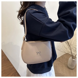 Close-up of beige leather crescent bag featuring a silver bow metal decoration