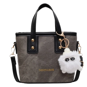 Sac seau gris texturé avec poignées en cuir noir et clous dorés sur fond blanc