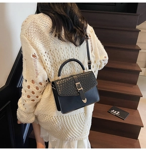Détail du sac bandoulière noir avec texture motif animal et poignée tissée en escalier