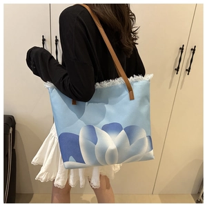 Detalle de bolso tote de lona con estampado floral, flecos y correas de cuero fino