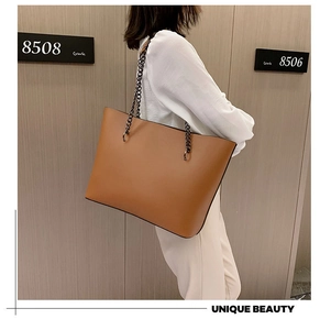 Detailed side view of a large caramel leather tote bag with stylish black metal chain handles