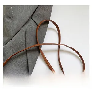 Detailed close-up of brown leather shoulder strap and stitching on a bucket bag