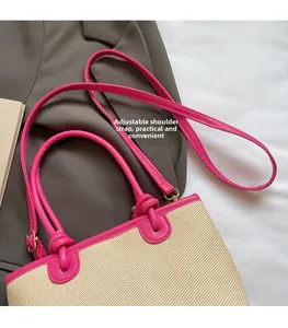 Détail de la bandoulière rose réglable sur un sac à main en paille tressée