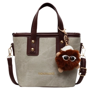 Retro two-tone green tote bag with brown leather handles and plush monster charm