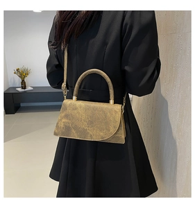 Detail view of metallic gold crossbody bag with vintage texture on black dress model