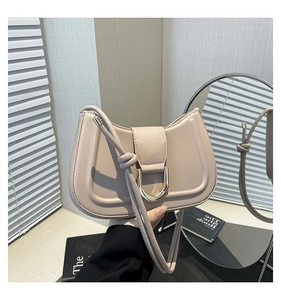 Detail view of beige crescent moon underarm bag with gold metal buckle and knotted strap